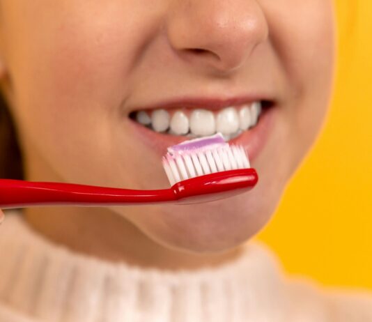 구강 건강과 전신 건강의 연관성: 구강 질환이 미치는 영향 girl with red and white toothbrush in mouth