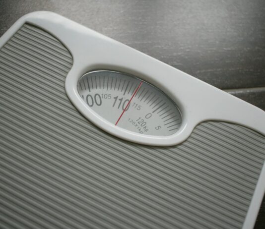 건강을 위한 동반자로서 다이어트와 운동 a bathroom scale sitting on top of a wooden table