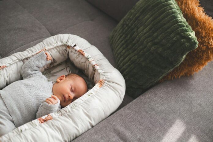 A newborn baby sleeps peacefully in a cozy nest.