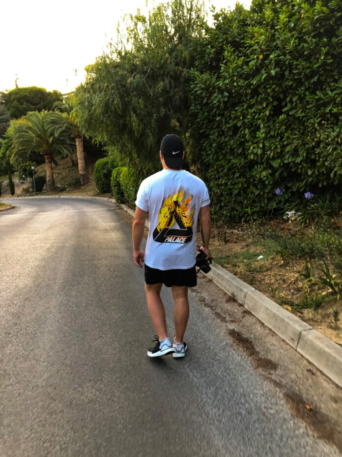 Photo by Casper Pedersen man walking on road beside trees