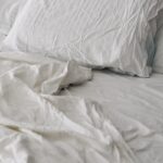 바쁜 일상 속 ‘슬기로운 숙면 습관’…한국인의 최신 수면 트렌드와 실생활 꿀팁 A rumpled white duvet and pillows on a bed.