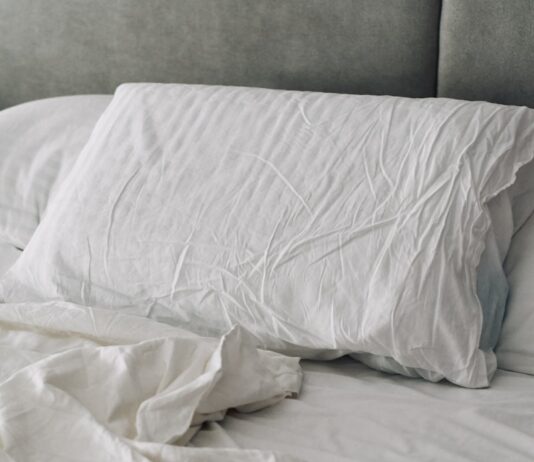 바쁜 일상 속 ‘슬기로운 숙면 습관’…한국인의 최신 수면 트렌드와 실생활 꿀팁 A rumpled white duvet and pillows on a bed.