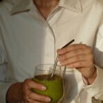 일상 속에서 꽃피는 웰니스 문화, 새로운 건강 트렌드와 실천법 person in white button up shirt holding clear drinking glass with green liquid