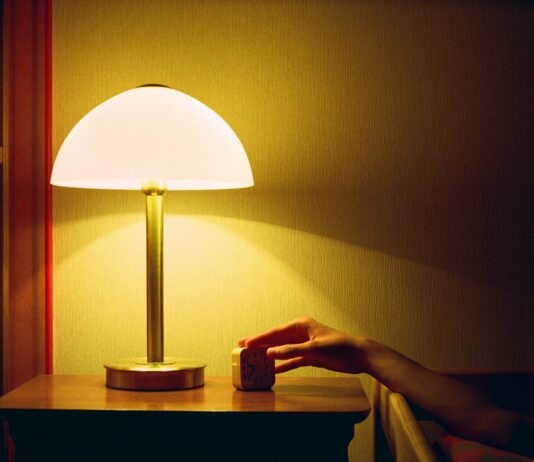 집에서 쉽게 실천하는 ‘스마트한 수면 루틴’이 주목받는다 a person's hand on a table next to a lamp